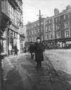 [Man in overcoat and bowler hat standing on St. Stephen's Green, with Grafton Street visible in background]