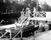 [People boarding a small boat, docked at a jetty]