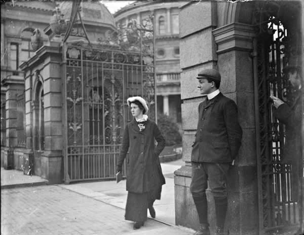 Woman wearing orthopaedic shoe, walking through the gates of Leinster House, Kildare Street. Man standing to the left of the woman, National&nbsp;...