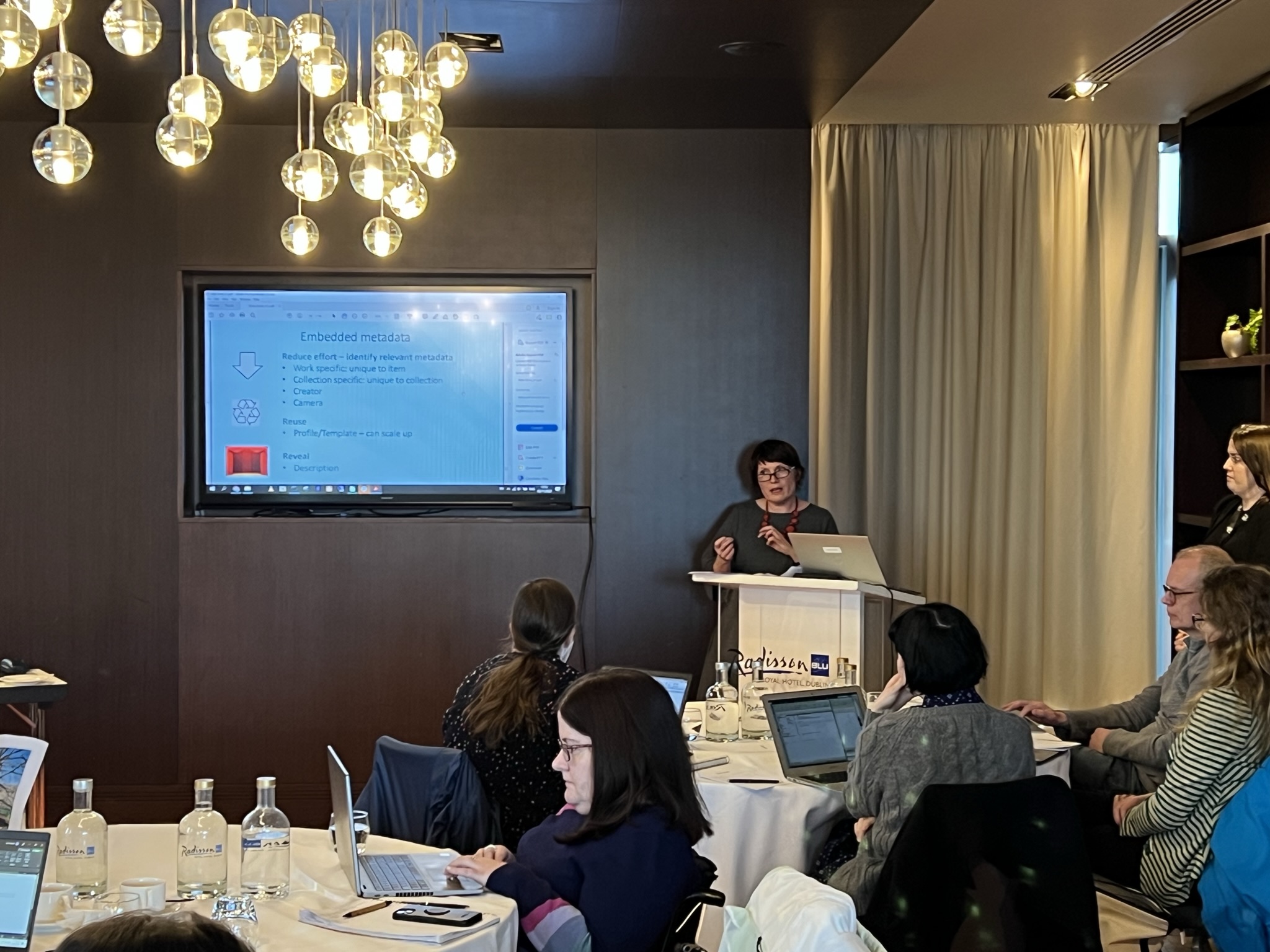 Woman presenting to a room full of people at the Radisson Blu Hotel 