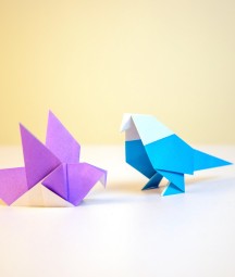 A purple and blue origami bird on a white table 