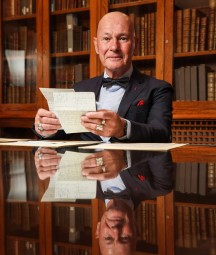 Bernárd Lynch seated in boardroom holding papers