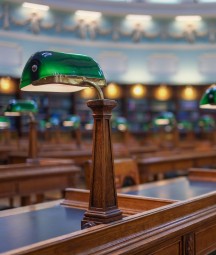 Seomra léitheoireachta folamh, sraitheanna deasc agus síleáil mhór chruinneachánach ar dhath gorm agus bán