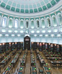 Empty reading room with rows of desk and large blue and white domed ceiling