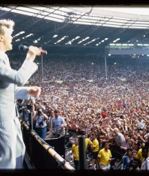 David Bowie performing at Wembley, with audience and photography pen in background