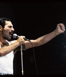 Freddie Mercury performing at Wembley, mic in left hand and right hand in a fist]