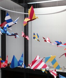 An artwork by Mazer of paper birds taking flight in a spiral