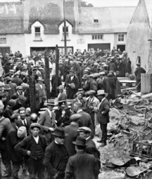 burnt out building, people looking into coffins.
