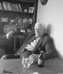A black and white photo of Patrick Heaney sitting at his kitchen table