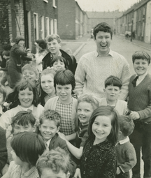 Heaney as a young man standing on the street surrounded by school children