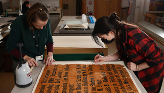 Two people working on conserving an old poster