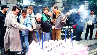 A group of protestors light a giant birthday cake outside the Government building gates