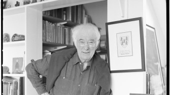 Black and white photograph of Seamus Heaney. White haired man wearing a shirt.