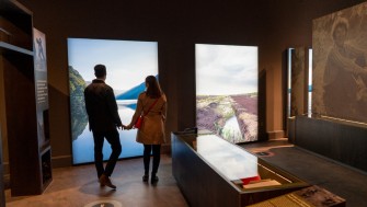 couple standing within exhibition space looking at images of the irish landscape