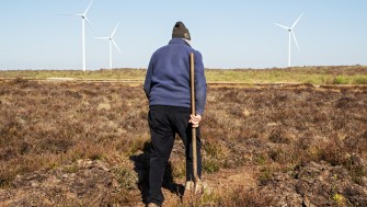 An image of person in a warm jumper in hat as they walk across the bog