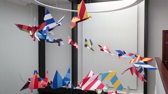An artwork by Mazer of paper birds taking flight in a spiral