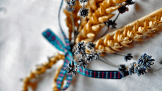 An image showing a harvest bow, which is wheat stalks and lavender weaved into a bow tied together by a ribbon