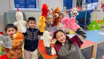 A group of children with story telling puppets posing together