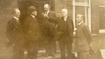 The members of the Boundary Commission standing in a line outside at its first sitting.