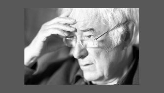 A black and white close up on Heaney looking introspective with his hand on his forehead