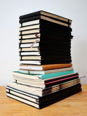 A pile of sketchbooks stacked on top of each other