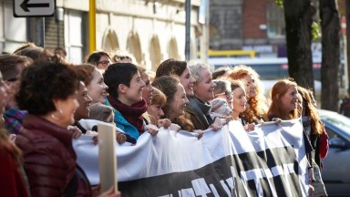 A number of women holding up a large banner