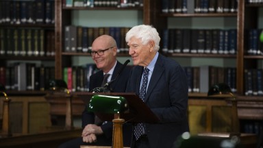 Joseph Hassett addressing an audience standing at a podium inside the NLI's Reading Room