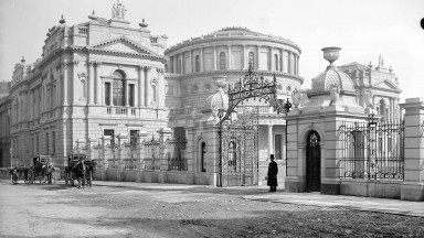 Grianghraf dubh agus bán d’fhoirgnimh Leabharlann Náisiúnta na hÉireann ar Shráid Chill Dara le dhá chapall agus cairt ar na sráideanna taobh amuigh