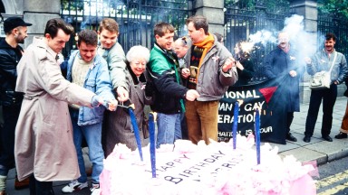 A group of protestors light a giant birthday cake outside the Government building gates