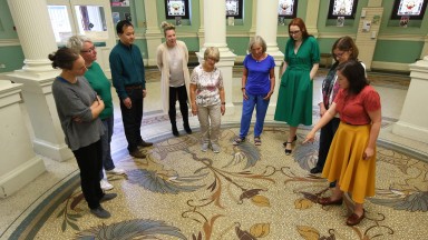 A guide points out a detail in the floor mosaic at the entrance to the National Library of Ireland to a group of visitors