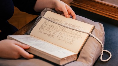 Image of hands holding a book on a cushion