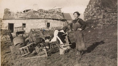 Sean-ghrianghraf d’Iníon de Brún agus giuirléidí s’aici timpeall uirthi, taobh amuigh dá teach ar An Maoilinn, Co. Chorcaí, a scriosadh in ionsaí díoltais ag na Dúchrónaigh. 7 Eanáir 1921