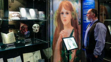 A well-dressed man looks at a display case full of WB Yeats exhibition material 