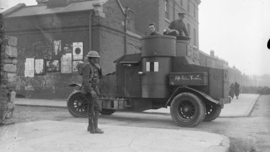 A black and white photo of a soldier standing next to an armoured car at the entrance to Mountjoy Prison 