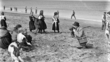 Image of man taking photo of children on the beach