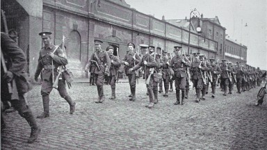 Soldiers in uniform march in ranks outside barracks