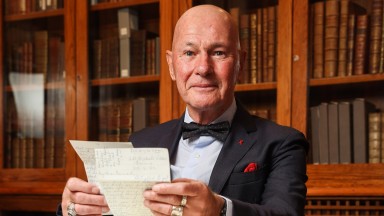 Bernárd Lynch seated in boardroom holding papers