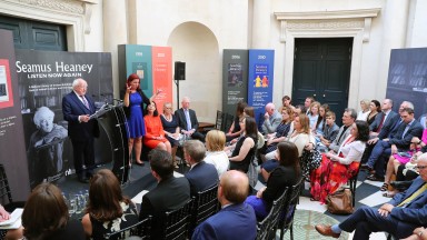 A group of people listening to speech by President of Ireland, Michael D. Higgins at launch of 'Seamus Heaney: Listen Now Again'. An ISL interpreter stands beside the President.