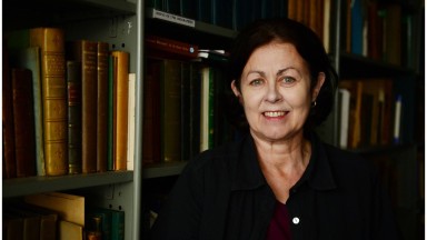 Photograph of Dr. Bairbre Ni Fhloinn standing against bookshelves