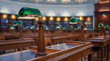 Seomra léitheoireachta folamh, sraitheanna deasc agus síleáil mhór chruinneachánach ar dhath gorm agus bán