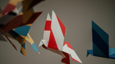 Photograph of a colourful paper birds art installation.