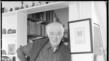 Black and white photograph of Seamus Heaney. White haired man wearing a shirt. 
