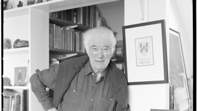 Black and white photograph of Seamus Heaney. White haired man wearing a shirt.