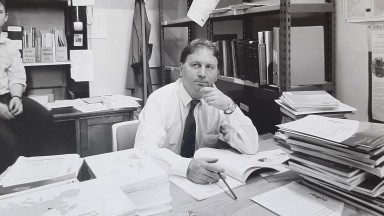 Black and white photograph of a man sitting at a desk