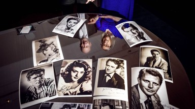 Dr Audrey Whitty and Liam Bluett looking down on photographic collection on a glass table