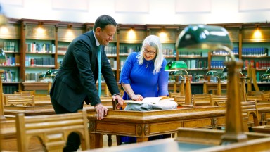 Former Taoiseach Leo Varadkar and Dr Audrey Whitty looking at a book on a desk inside of the NLI's Reading Room