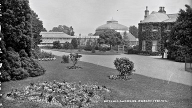 Black and white image of the National Botanic Gardens in Dublin with a lawn and greenhouse in the background.