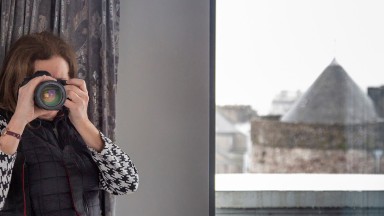 An image of the photographer Paula Nolan, from behind her camera. Waterford city can be seen from the window