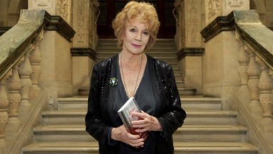 Edna O'Brien holding book standing on stairs at the NLI