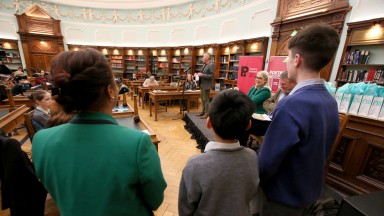 The backs of three children participating in Poetry Aloud 2023